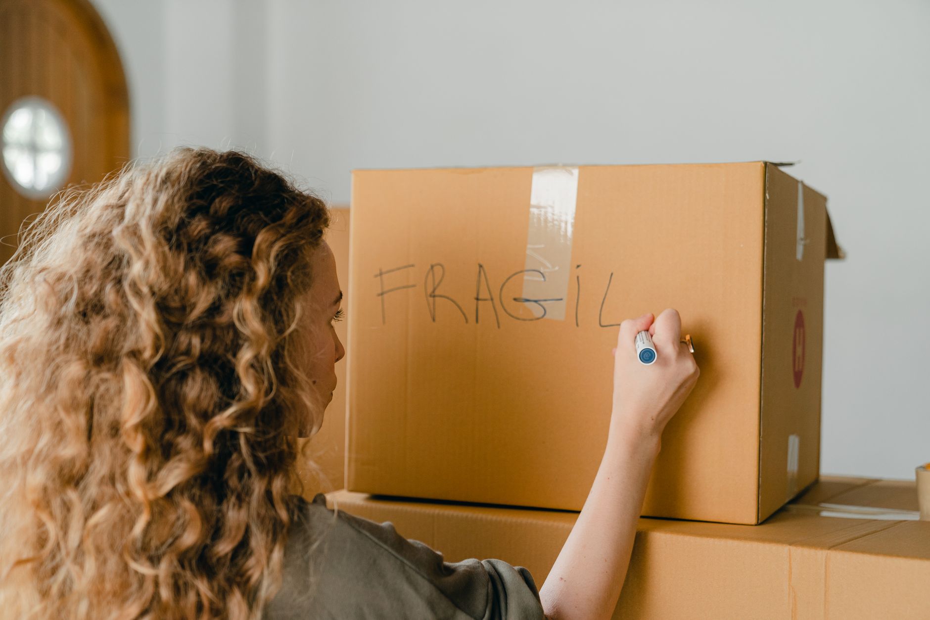 Cartons de déménagement étiquetés par pièce posés sur un parquet